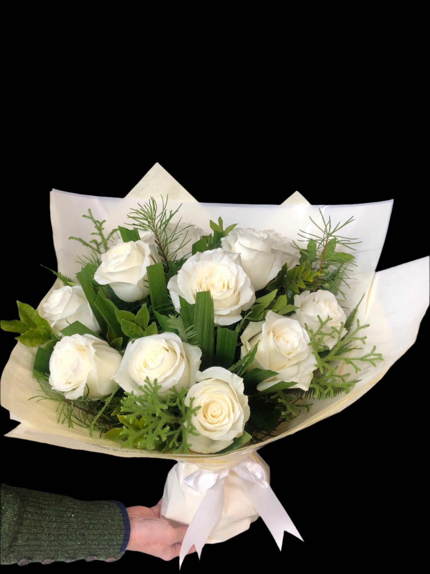 Bouquet of white roses with greenery on a dark background.